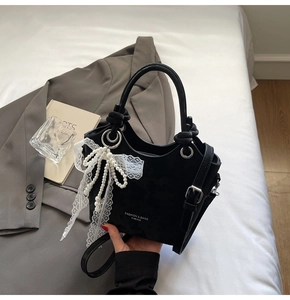 Détail du sac cabas noir avec nœud en dentelle de perles et bandoulière réglable