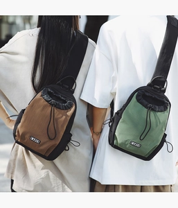 Rückansicht von Paar mit braunen und grünen Ripstop-Nylon-Brusttaschen mit Kordelzug