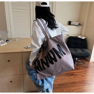 Detailed close-up of large canvas tote bag with MNWM lettering on a shoulder strap