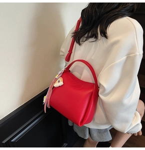 Détail du sac seau rouge en cuir grainé avec breloque arc-en-ciel et bandoulière
