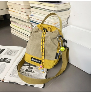 Detail shot of a color-block crossbody bag featuring drawstring closure and tennis charm