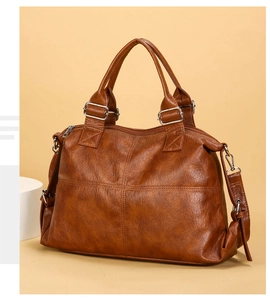 Close-up of brown oiled leather tote bag showing handle details and silver metal buckles