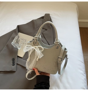 Détail du sac à main vert sauge texturé avec breloque décorative en perles et dentelle