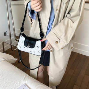 Details der weißen Handtasche mit Bogenmuster, Webgriff und silbernem Herzanhänger