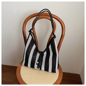 Detail of black and white striped tote bag with elegant knotted shoulder strap detail