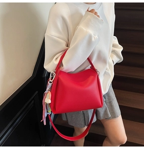 Détail du sac seau rouge texturé avec charm arc-en-ciel et ruban à carreaux décoratif