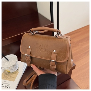 Detail of caramel leather bag showing PAN TOR logo and silver hardware buckles