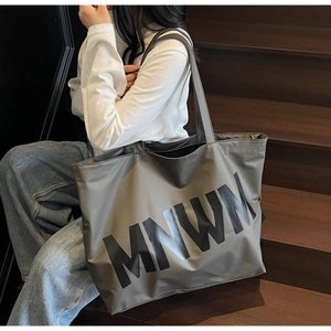 Detail of grey large-capacity tote bag with MNWM lettering on durable nylon fabric