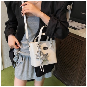 Detail of white crocodile embossed crossbody bag with star charm and metal logo plate
