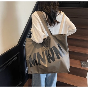 Deep olive oversized tote bag with MNWM print shown on model in a staircase setting