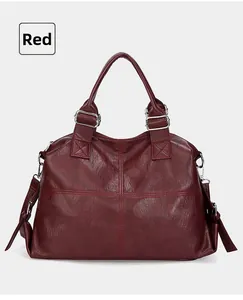 Detail of dark red faux leather tote showing the textured cross-stitched pattern and strap