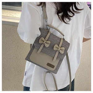 Detail of sweet bow design on grey fabric and beige leather patchwork backpack