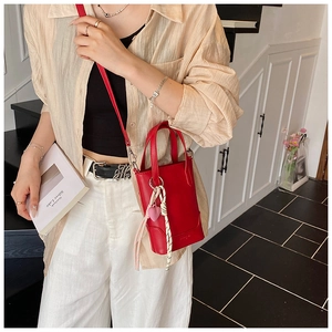 Détail du sac seau rouge en cuir avec pendentif cœur et bandoulière réglable