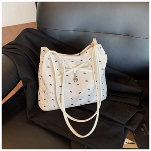 Gros plan d'un cabas blanc à motif nœuds noirs avec texture plissée et pendentif cœur