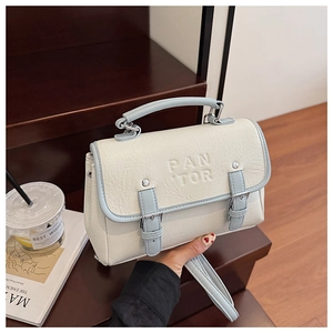 Detailed view of cream textured leather crossbody bag with blue trim and silver hardware