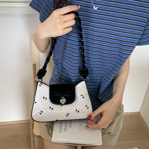 Detailansicht der Damen-Schultertasche mit Punkten, Herzanhänger und geflochtenem Riemen