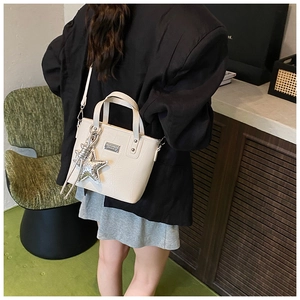 Detail of cream crocodile embossed bucket bag with silver star charm and shoulder strap