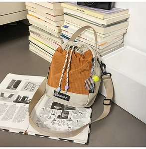 Detail of canvas bucket bag featuring orange checkered pattern and drawstring closure