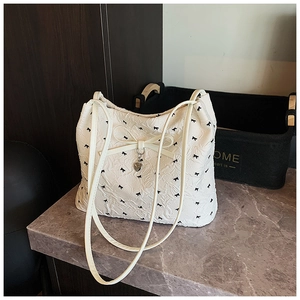 Détail du sac seau plissé blanc cassé avec motifs nœuds et pendentif cœur en métal
