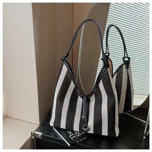 Detail of striped woven tote bag with leather trim and round metal buckle on circular mirror