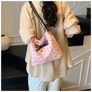 Sac seersucker rose avec nœuds noirs et pendentif cœur porté par un mannequin