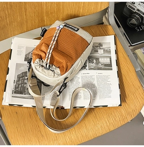 Detail of crossbody bag showing beige and orange grid texture with braided drawstring