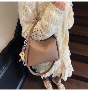Sac seau en cuir grainé marron avec charme arc-en-ciel porté à l'épaule pour femme