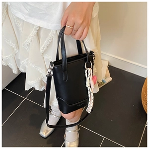 Détail du sac seau noir avec breloque cœur rose et bandoulière réglable pour femme