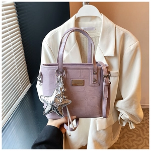 Detail of purple croc-effect crossbody bucket bag with silver star charm and metal plate