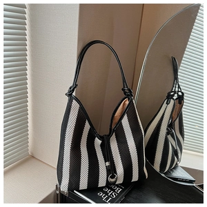 Detailed macro view of black and white striped woven tote bag with leather handle and drawstrings