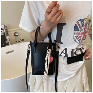 Détail du sac seau en cuir noir avec breloque cœur rose et bandoulière réglable
