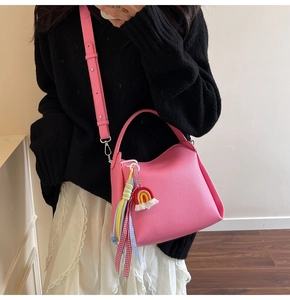 Détail du sac seau rose avec texture cuir grainé et pendentif pompon arc-en-ciel