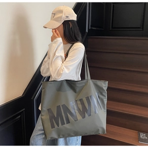 Detailed view of an olive green nylon tote bag with black MNWM letter print design