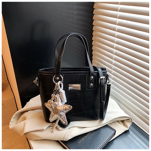 Close-up of black crocodile pattern tote bag with silver star charm and metal logo