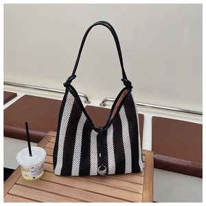 Close-up of black and white striped mesh tote bag with leather strap and metal detail