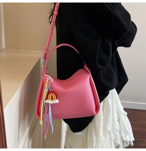 Sac seau rose en cuir grainé avec un pendentif arc-en-ciel tissé coloré en détail