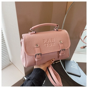 Detailed close-up of pink textured leather crossbody bag with metal rivets and brand logo