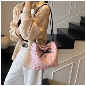 Détail du sac seau plissé rose avec imprimé nœud noir et pendentif cœur argenté