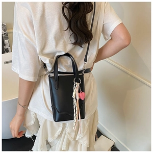 Détail du mini sac seau noir avec pendentif cœur rose et ruban à carreaux chic