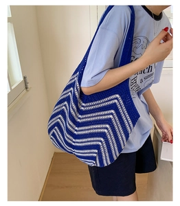 Dettaglio della borsa tote in maglia a righe blu e bianche con trama a uncinetto