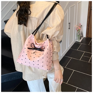 Détail du sac seau rose avec broderies de nœuds noirs et bandoulière en cuir chic