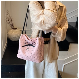 Détail du sac bandoulière rose clair avec texture plissée et nœud noir décoratif