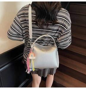 Détail du sac seau argenté avec pompon arc-en-ciel sur une tenue décontractée