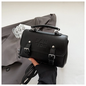 Detailed view of black faux leather handbag with dual buckles and embossed logo
