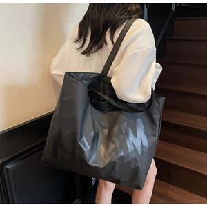Detail of wide shoulder strap and MUM letter print on black large capacity tote bag