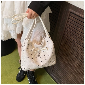 Détail du sac seau blanc avec motifs nœuds noirs et pendentif en forme de cœur