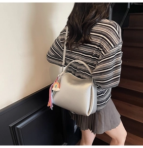 Gros plan du sac seau argenté en cuir grainé avec charme arc-en-ciel sur un modèle