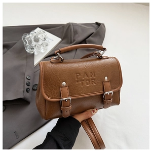 Close-up of brown PU leather bag with PAN TOR embossing and silver metal buckle detail