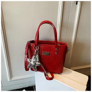 Detail of red crocodile texture handbag with silver star charm and metallic logo plaque
