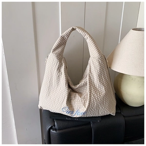 Detail of beige striped tote bag featuring Our fave embroidery and side zipper hardware